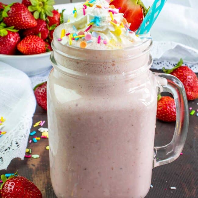 strawberry milkshake topped with whipped cream and sprinkles.