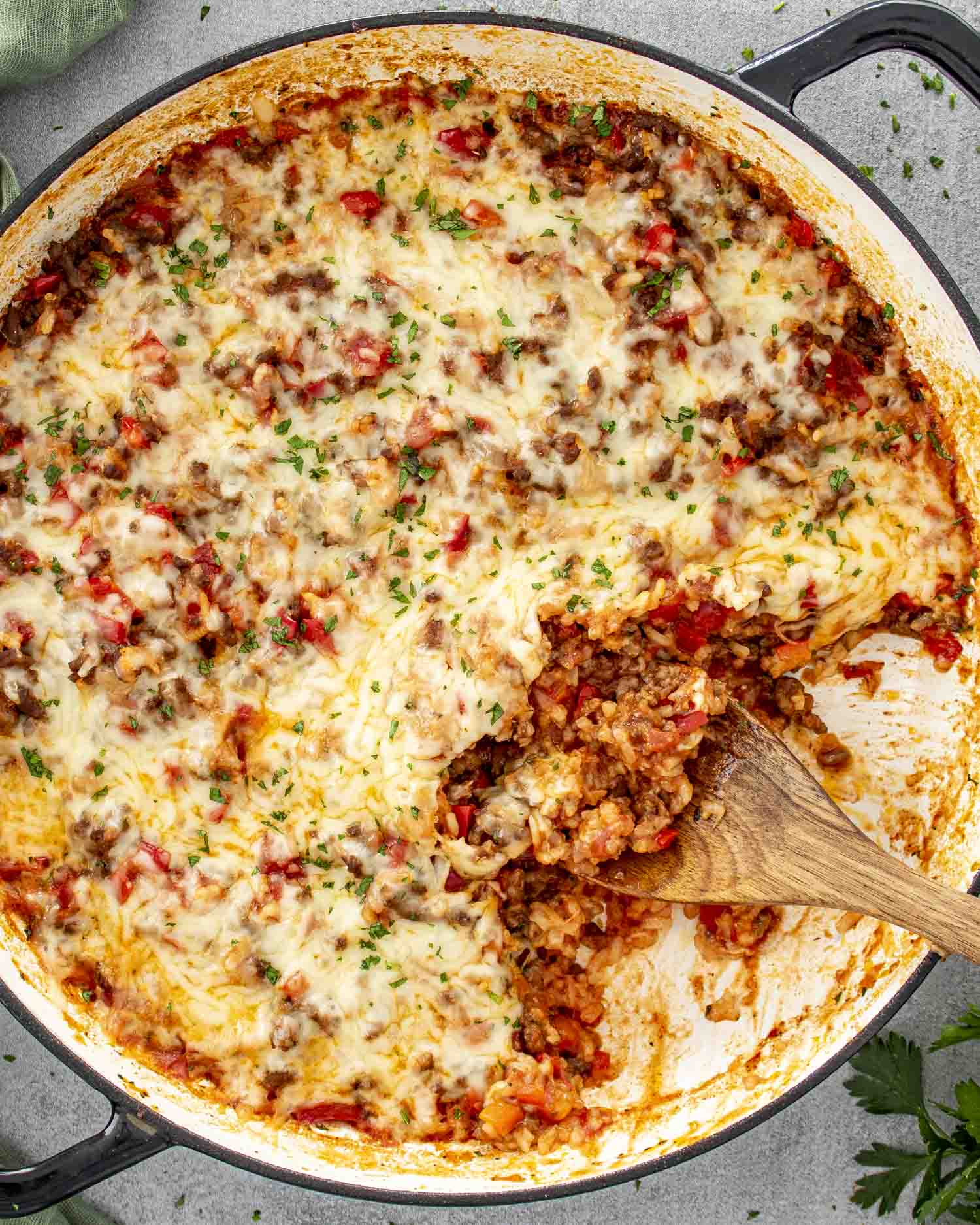 fresh out of the oven, stuffed pepper casserole in a pot topped with cheese and a sprinkle of parsley.