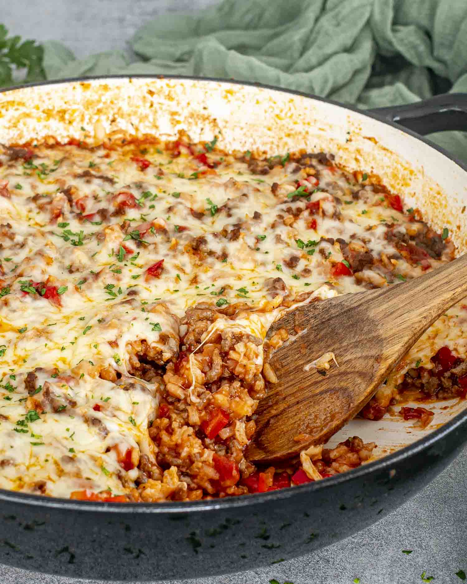 fresh out of the oven, stuffed pepper casserole in a pot topped with cheese and a sprinkle of parsley.