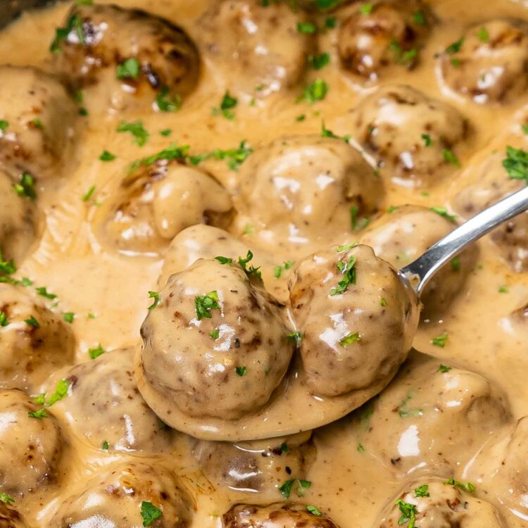 swedish meatballs with lots of sauce in a skillet, freshly made and garnished with parsley.