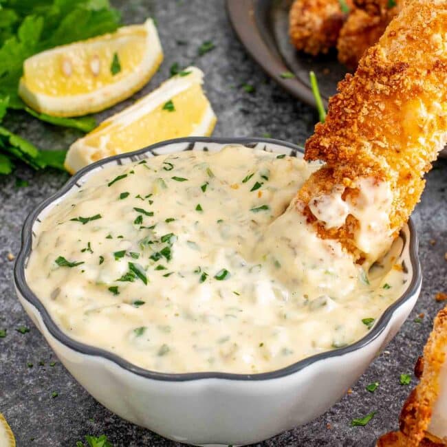 tartar sauce in a little dish with a fish stick in it.