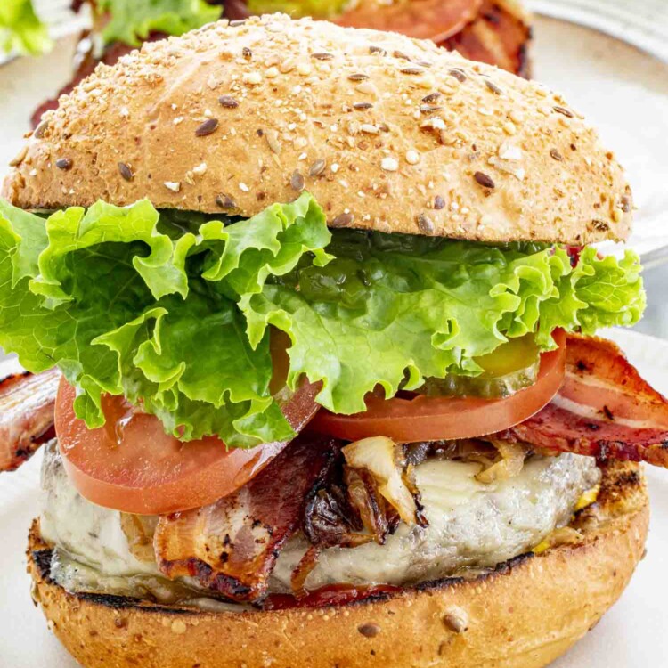 A juicy homemade burger with melted cheese, crispy bacon, fresh lettuce, tomato, pickles, and a toasted multigrain bun.