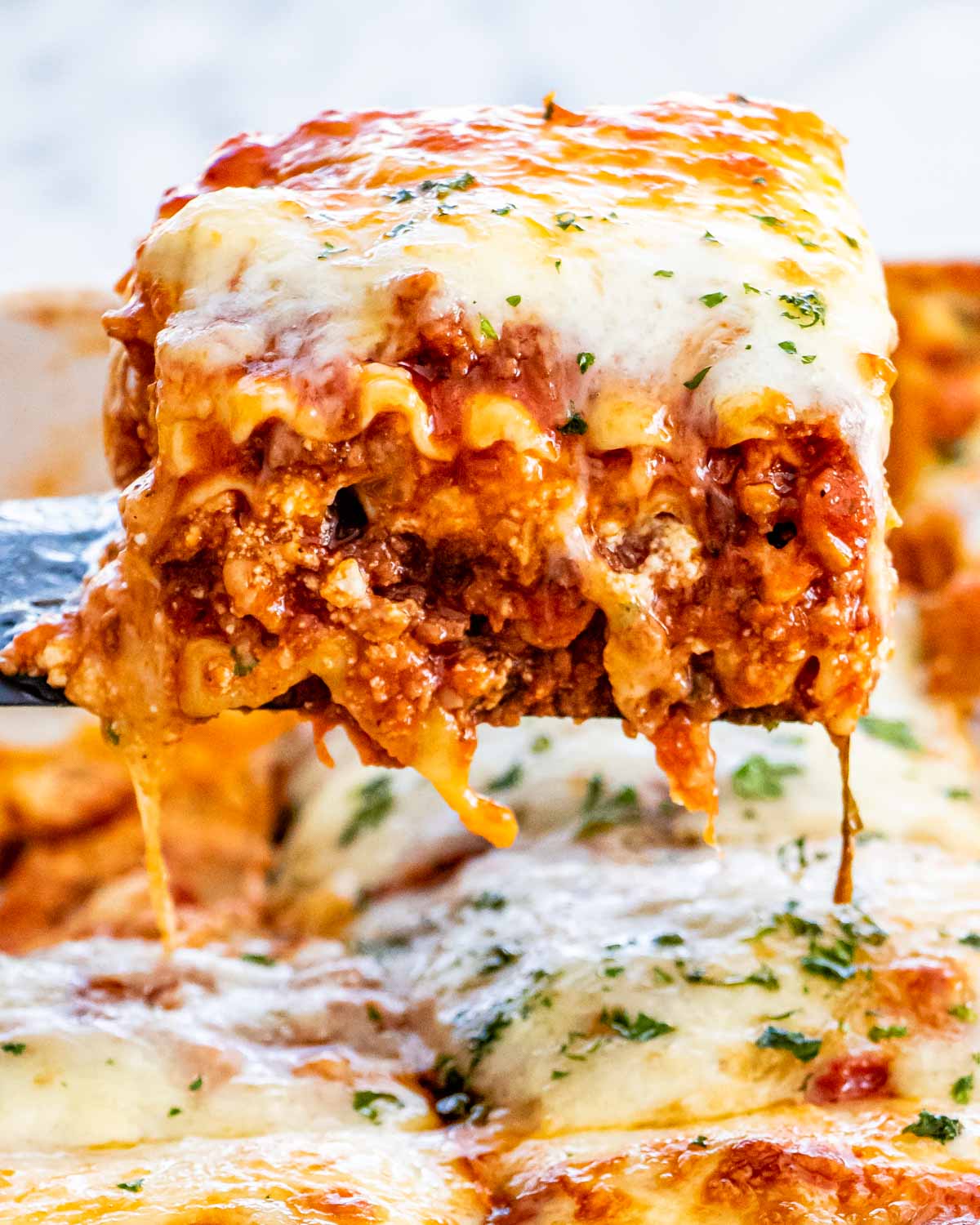 a spatula lifting a piece of lasagna from a casserole dish.