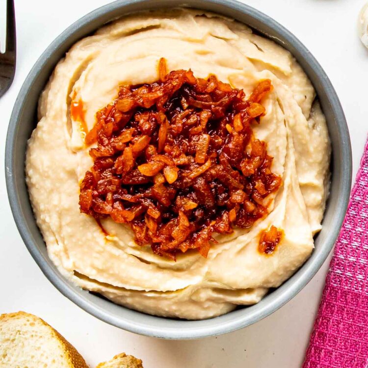 white bean dip with sauteed onions in a blue bowl.