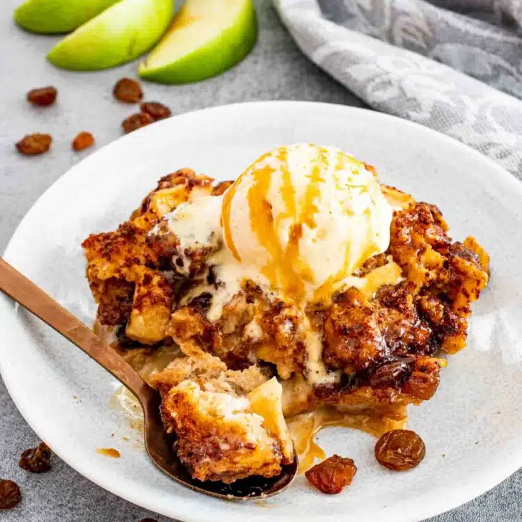 a serving of apple pie bread pudding on a white plate.