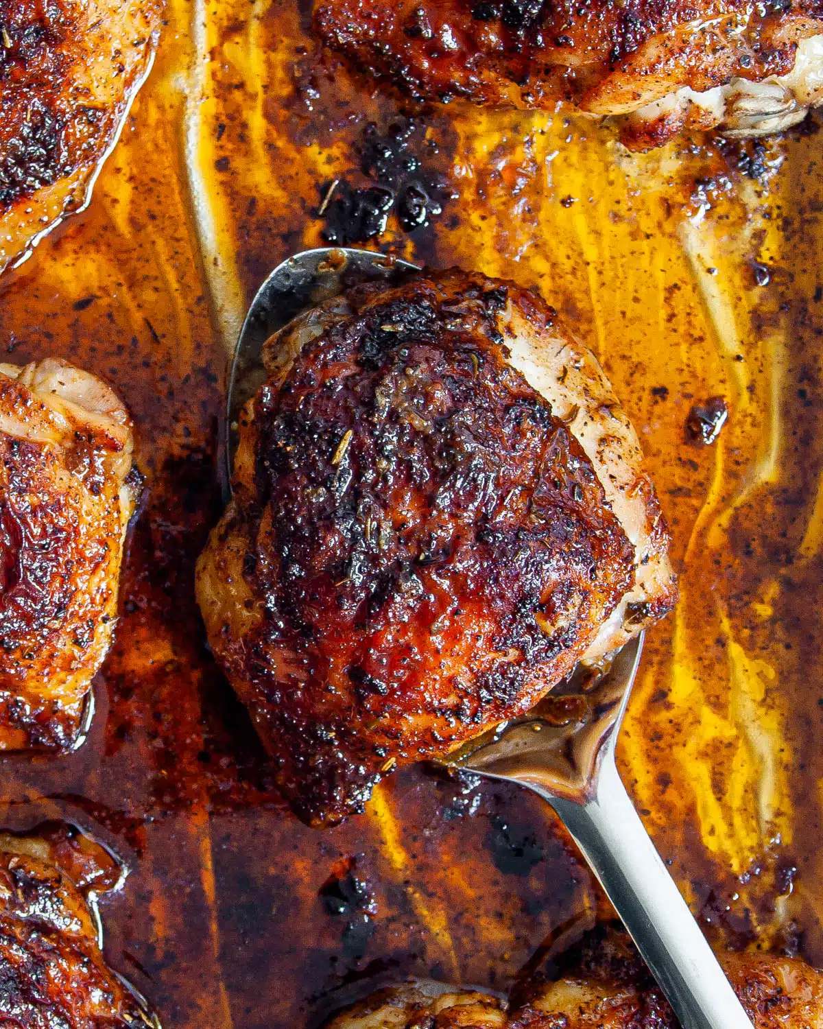 overhead shot of baked chicken thigh in a serving spoon