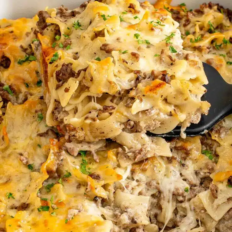 freshly baked beef stroganoff casserole in a white casserole dish garnished with parsley.
