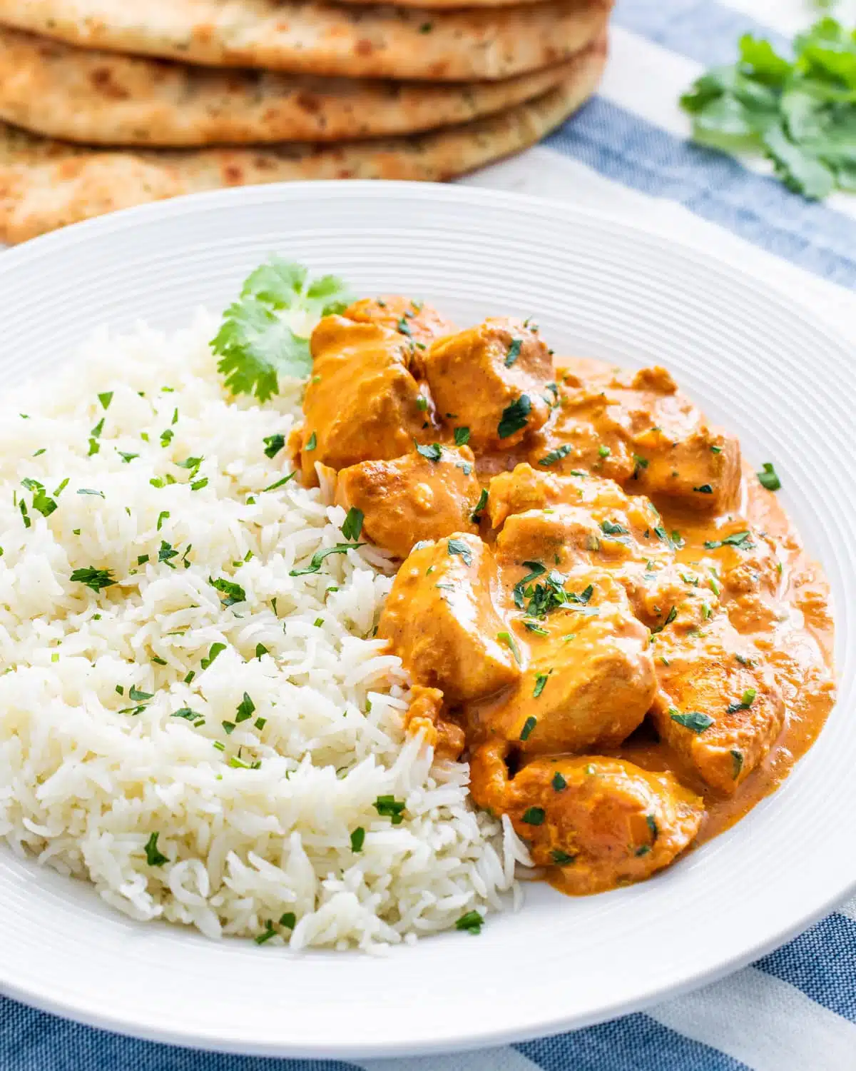 butter chicken in a white plate next to a side of rice