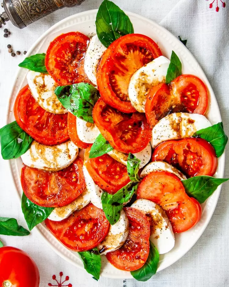 overhead shot of a beautifully layered caprese salad on a white platter