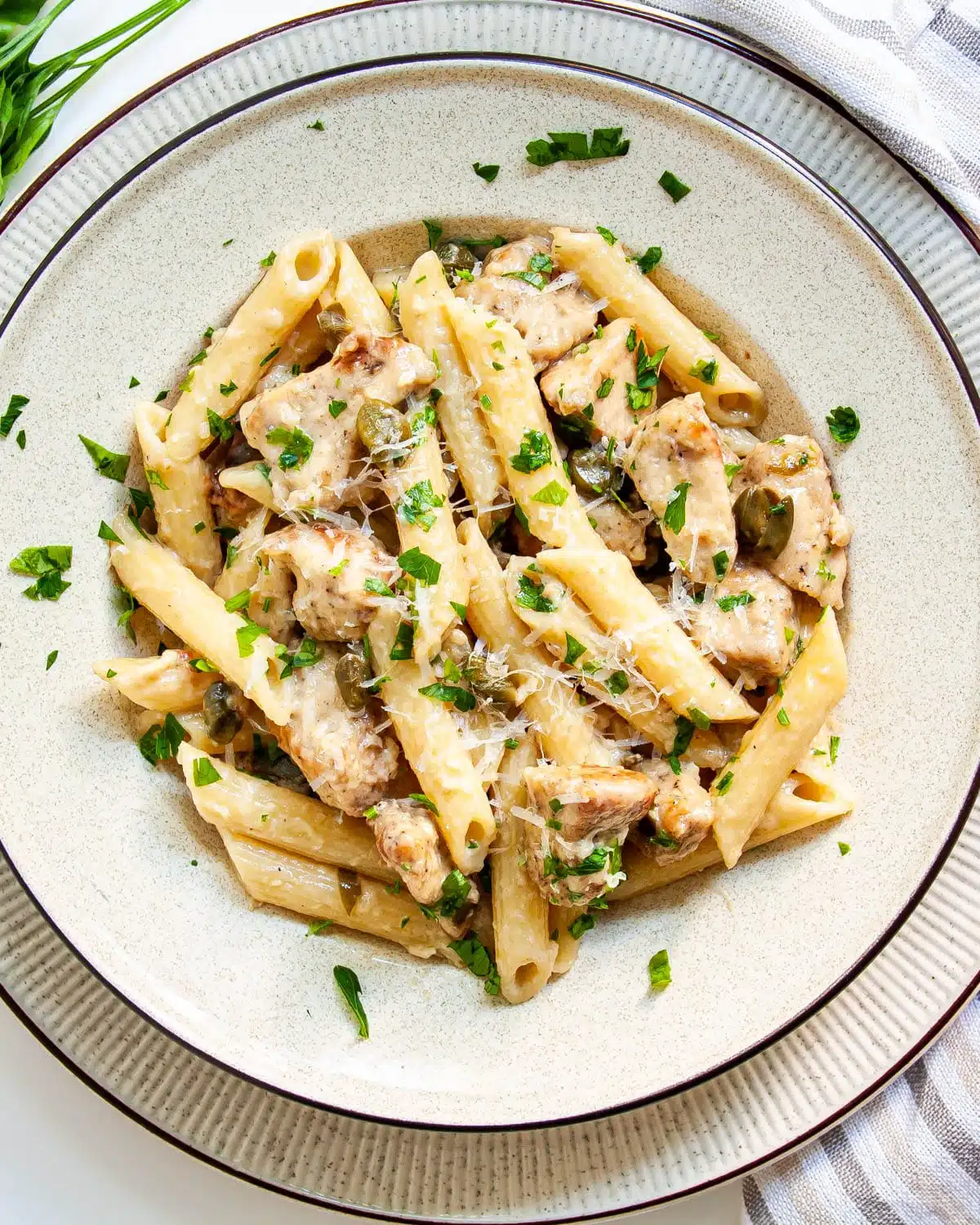 overhead shot of chicken piccata pasta on a plate garnished with parsley