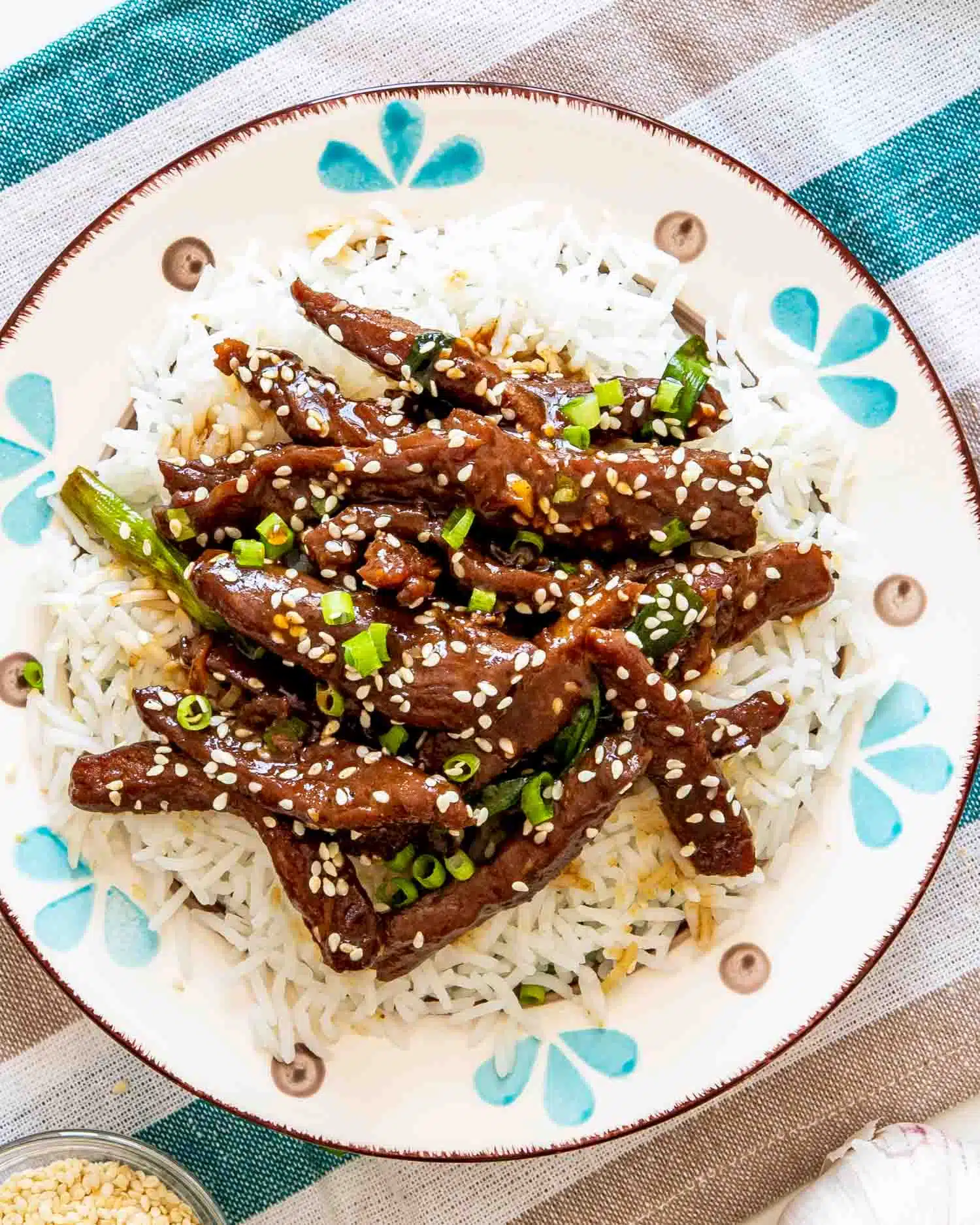chinese sizzling beef on a bed of rice in a plate.