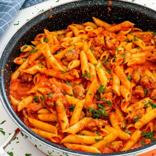 freshly made creamy red pepper pasta in an orange skillet.
