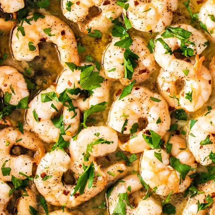 freshly made garlic butter shrimp in a skillet garnished with fresh parsley.