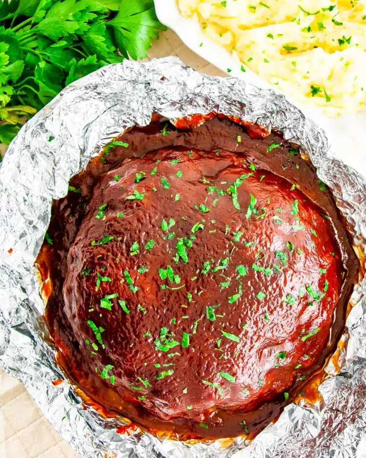 overhead shot of meatloaf in aluminum foil next to a bowl full of mashed potatoes