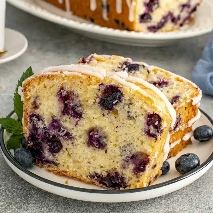 Soft lemon blueberry bread with icing drizzle, sliced and served with fresh blueberries, showing fluffy interior and golden crust.