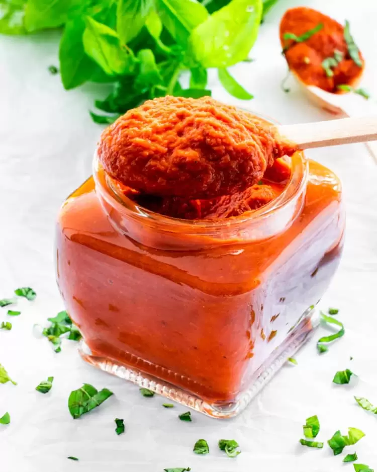 a spoon taking out some marinara sauce from a jar