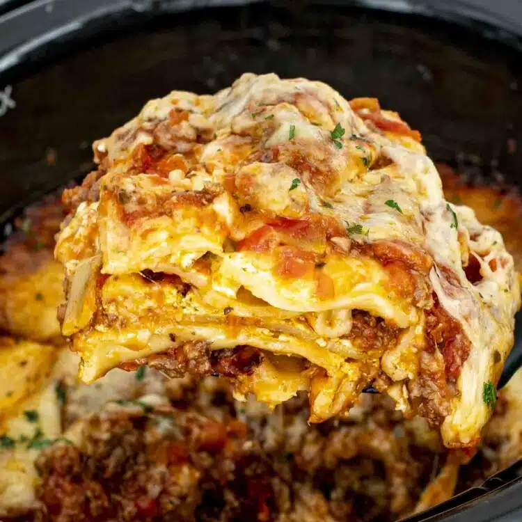 a spatula lifting a slice of lasagna from the slow cooker.
