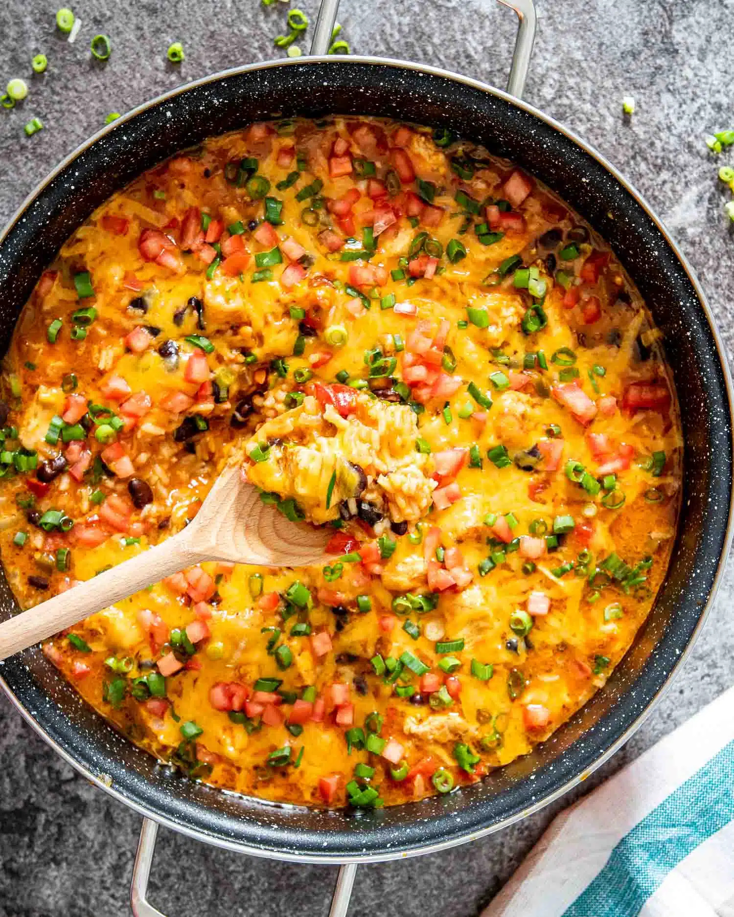 southwest chicken and rice in a skillet with a wooden spoon inside.